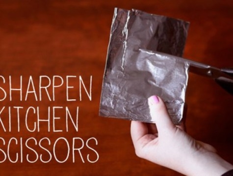 person sharpening scissors with aluminum foil