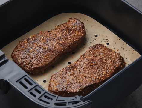 steaks sitting in a parchment lined air fryer basket