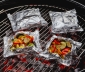 Foil packets with roasted vegetables sitting on a charcoal grill