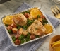 Baking sheet covered in aluminum foil and topped with roasted chicken, potatoes, spinach and lemons