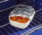 Casserole dish filled with sausage and peppers partially covered with aluminum foil