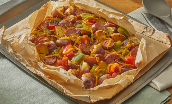 breakfast hash with melted cheese sitting in an open parchment cooking bag