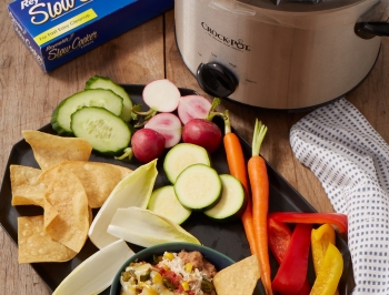 Cheesy Jalapeno Dip in a slow cooker lined with a Reynolds slow cooker liner alongside diced vegetables