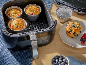 Air fryer cups filled with various flavored muffins sitting in an air fryer basket
