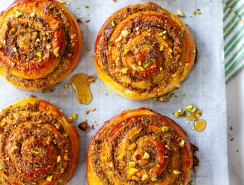 Pistachio Honey Cinnamon Rolls sitting on a sheet of Reynolds parchment paper on a wire cooling rack